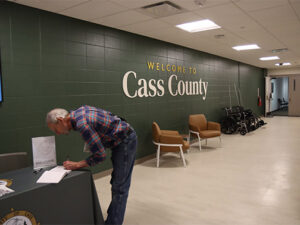 a man is signing the guest book at the grand reopening and 125th anniversary of the Cass County Administration building